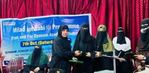 A presenter handing an award to a student during the Milad-un-Nabi ﷺ event at Gyanam Junior College."