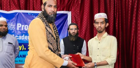"A presenter handing an award to a student during the Milad-un-Nabi ﷺ event at Gyanam Junior College."