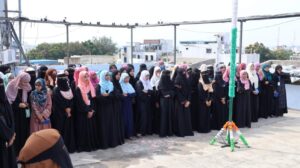 Flag hoisting ceremony at Gyanam Junior College on Independence Day with students performing cultural programs in the background.